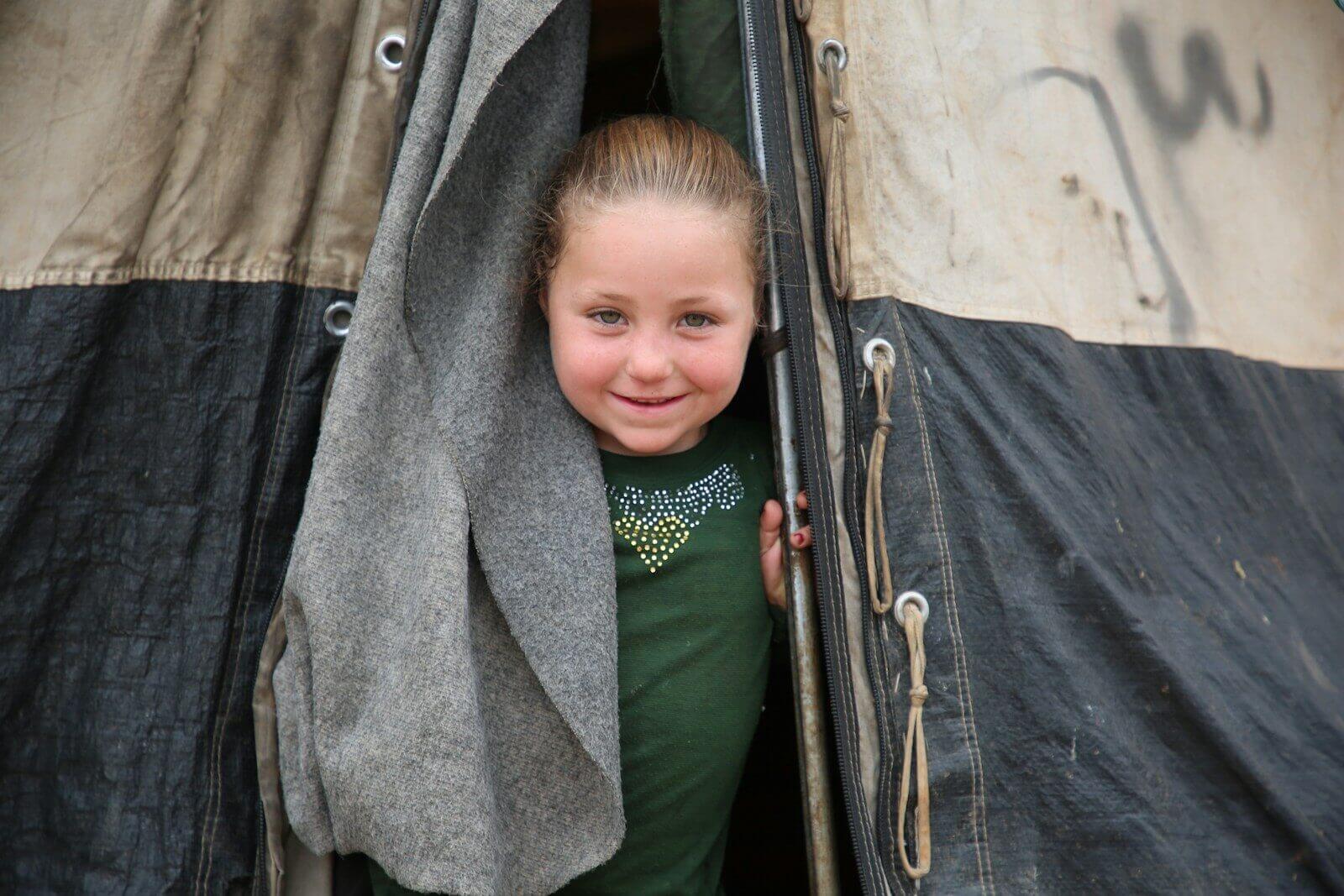 A young girl standing inside of a black and white tent